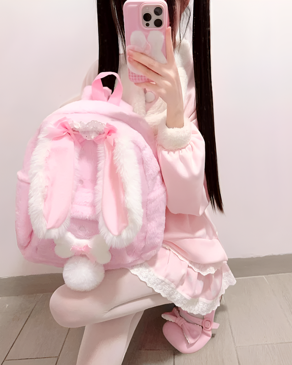 Pink rabbit eared backpack worn by a person.