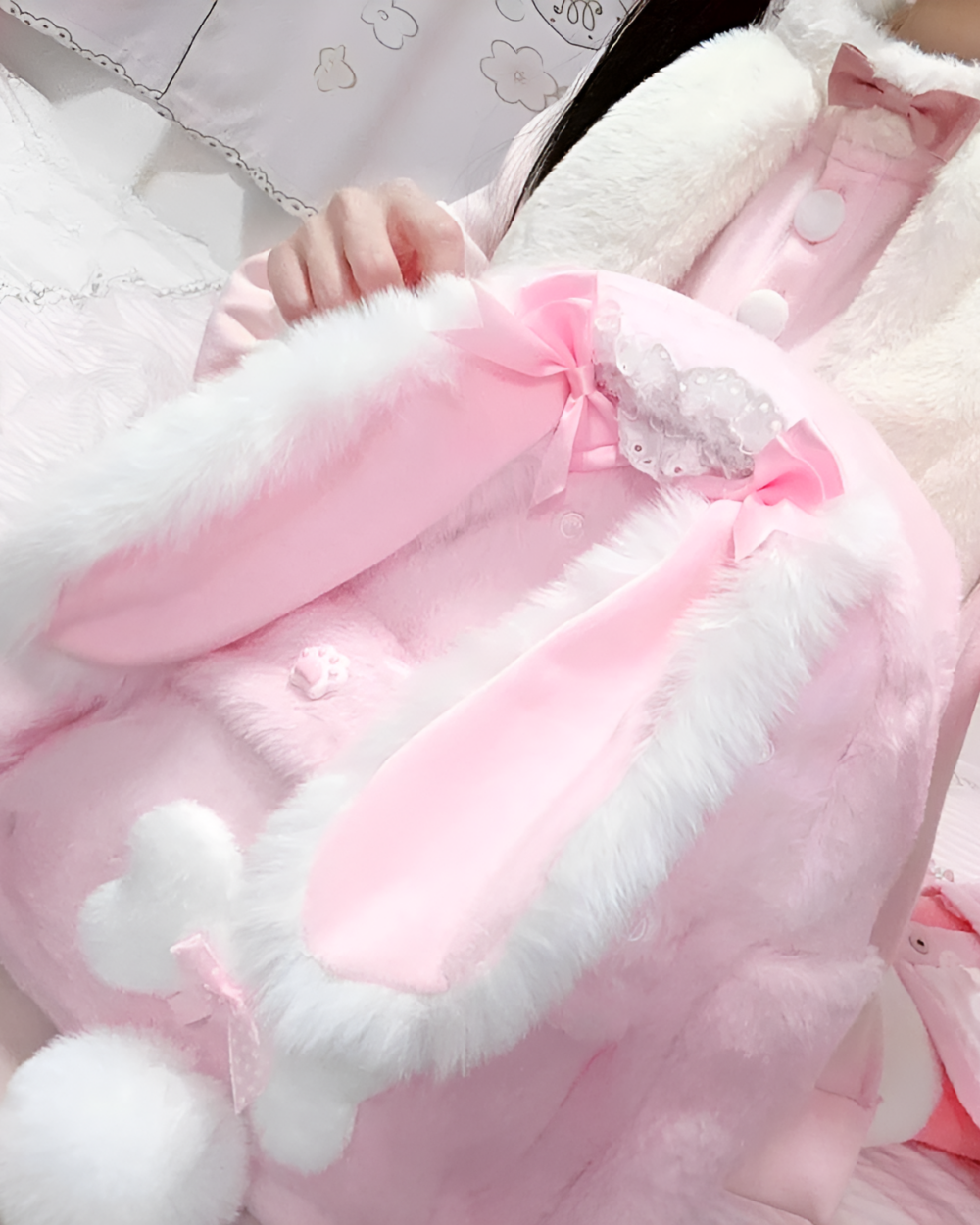 Pink rabbit eared backpack with fluffy trim and bow details.