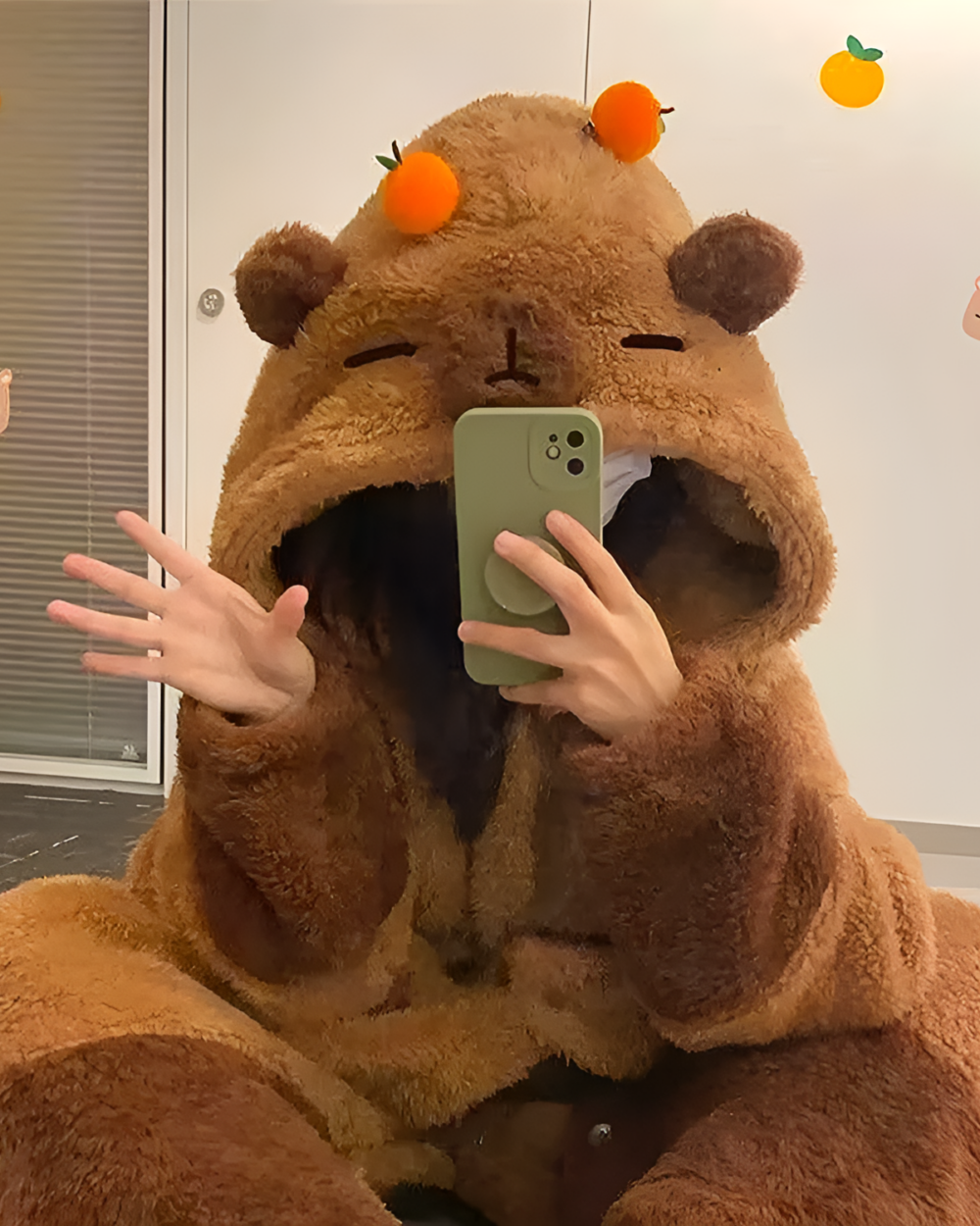 Person wearing a brown bear Fluffy Kigurumi with orange accents, holding a phone and posing for a selfie.