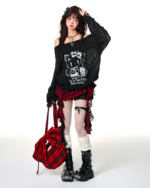 Model wearing a black top and a red and black gothic pleated skirt with platform boots and accessories.