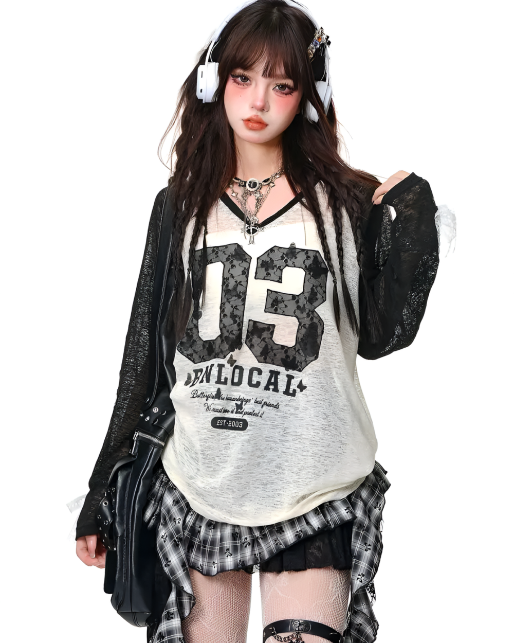 Model wearing a white graphic tee and a black and grey gothic pleated skirt. Styled with headphones and a jacket.
