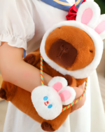 Hatted capybara plushie purse edition with a squeaker, shown being held. Features a brown capybara plush with a white hat.