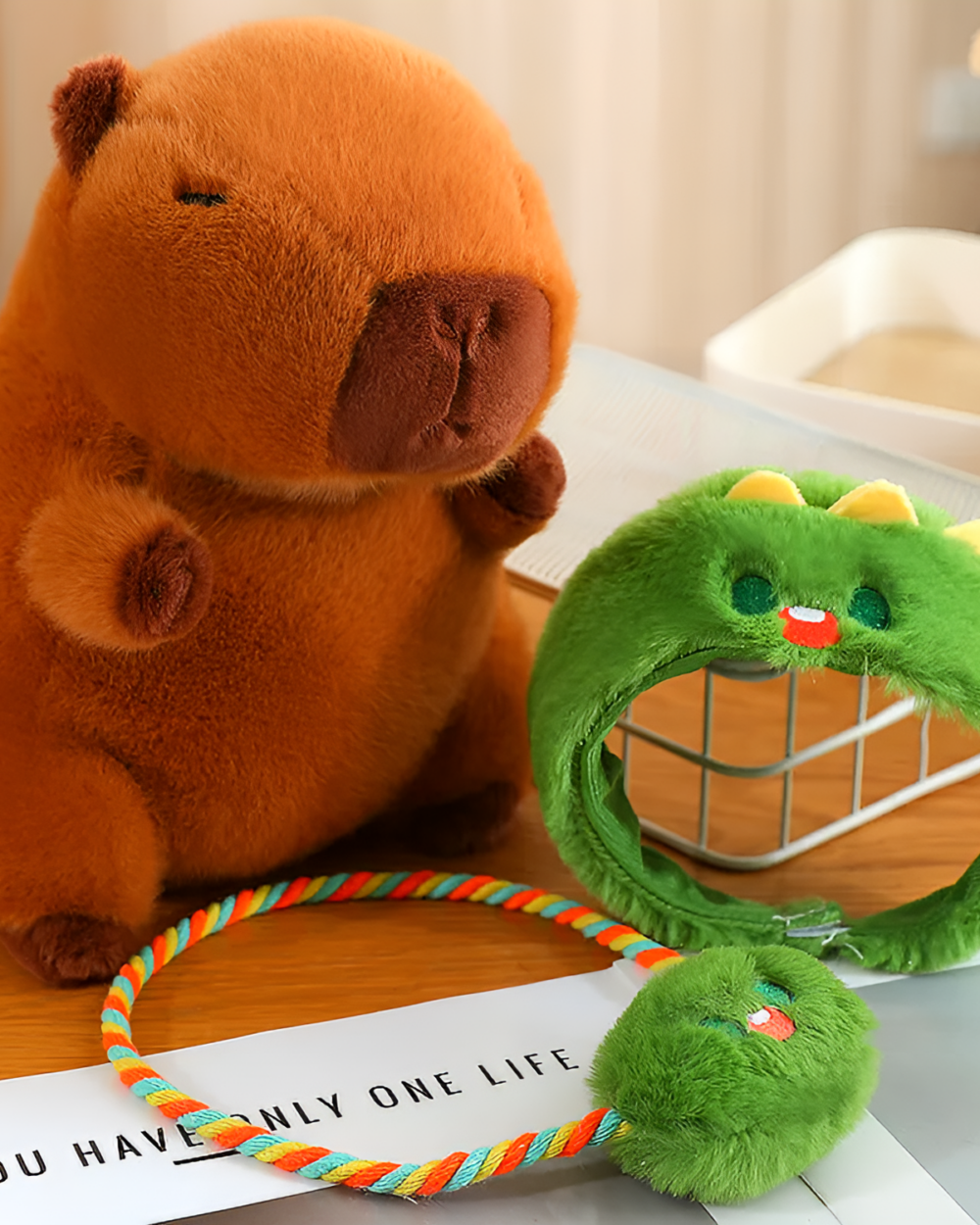 Close-up of brown and green Hatted Capybara Plushies with a colorful strap, designed as a squeaky purse.