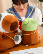 A person holding three Hatted Capybara Plushies - Squeaky Purse Edition. These capybara plushie toys are brown, white, and green.