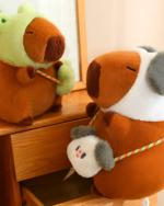 Close-up of Hatted Capybara Plushies - Squeaky Purse Edition. Two brown capybara plushies with hats and straps are shown.