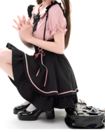 Pink and black Jirai Kei outfit with lace-up pinafore and ruffled details. Features a coordinating top and high-heeled shoes.