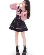 Model wearing a pink and black Heartache Lace-Up Pinafore Coord, a Jirai Kei outfit with a ruffled collar and lace-up detailing.