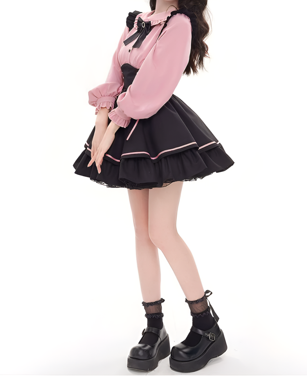 Model wearing a pink and black Heartache Lace-Up Pinafore Coord, a Jirai Kei outfit with ruffled skirt and long sleeves.