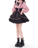 Model wearing a pink blouse and black Heartache Lace-Up Pinafore Coord, showcasing a Jirai Kei outfit with lace and ribbon detailing.