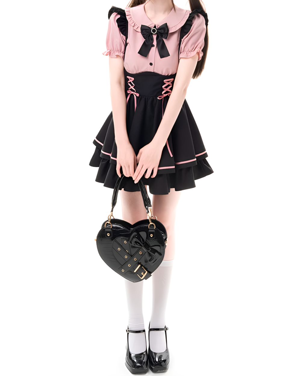 Model wearing a Heartache Lace-Up Pinafore Coord, a Jirai Kei outfit with a pink top, black skirt & heart-shaped bag.