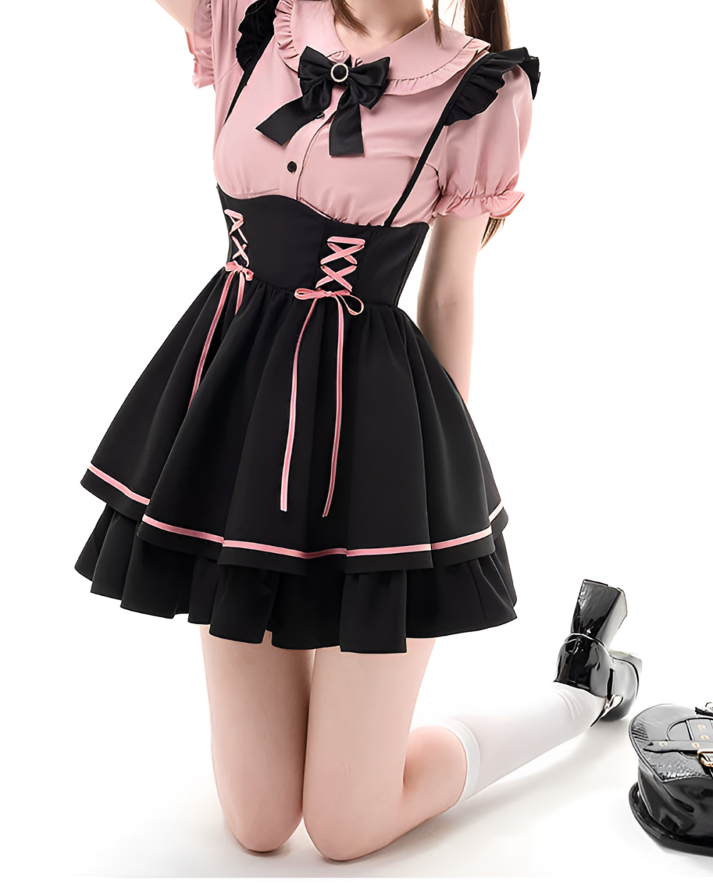 Model wearing a pink and black Jirai Kei outfit with lace details and a pinafore style. Includes a ruffled collar and lace-up accents.
