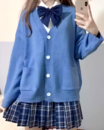 Woman wearing a blue JK cardigan sweater with a plaid skirt. Oversized fit with button closure.