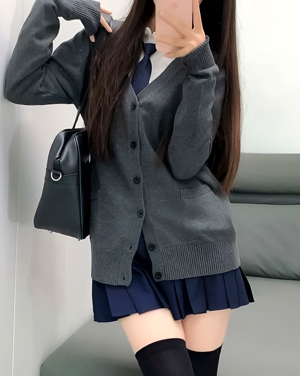 Woman wearing a gray JK cardigan sweater over a blue dress and black thigh-high socks. The cardigan has buttons.