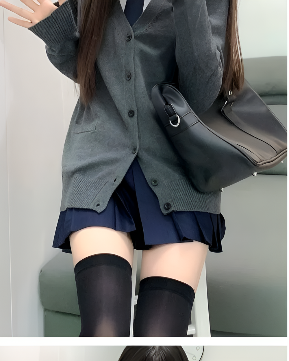 Woman wearing a gray JK cardigan sweater with a pleated skirt and black socks.