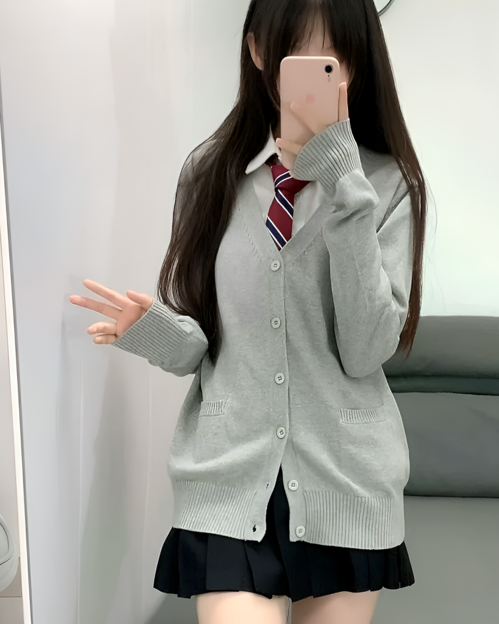 Woman wearing a gray JK cardigan sweater with a white shirt and plaid tie, posing for a mirror selfie.