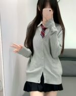Woman wearing a gray JK cardigan sweater with a white shirt and plaid tie, posing for a mirror selfie.