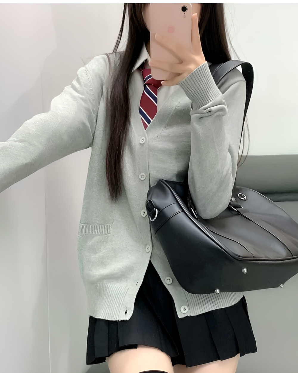 Woman wearing a gray JK cardigan sweater with a black skirt and bag. Casual, preppy style.