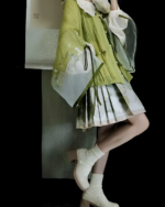 Woman wearing a green Jade Blossom Neo-Hanfu set with floral details and white boots. A modern take on traditional Chinese clothing.