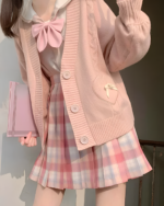 Pink Japanese knitted cardigan with a bow detail and pleated skirt.