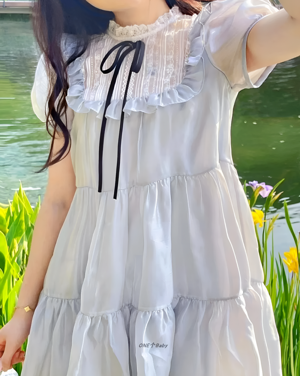 Close-up of a white japanese mesh dress with ruffles and a black bow detail.