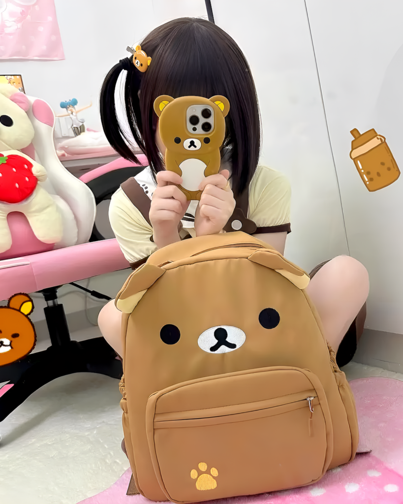 A person holding a phone case and wearing a Kawaii Bear Backpack - Jojifuku. The brown backpack features a bear face design.