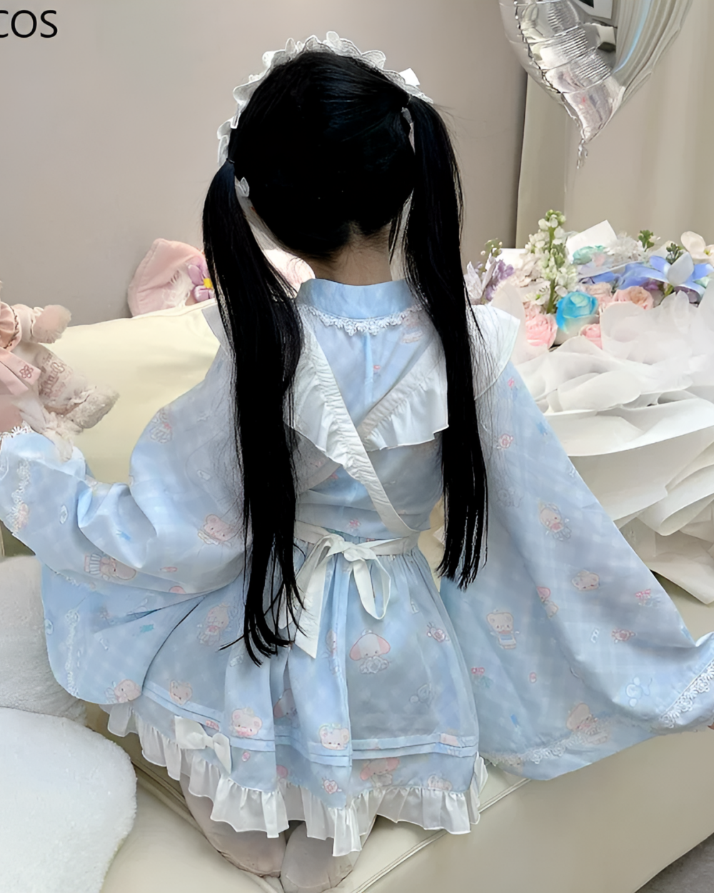 A person wearing a blue lolita style dress with ruffled details and bear motifs.