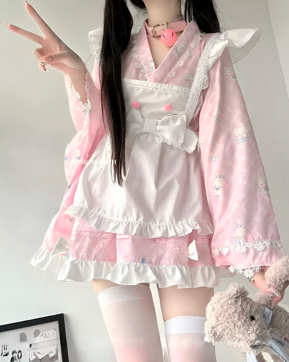 A pink lolita style dress with ruffles, lace, and kawaii motifs.
