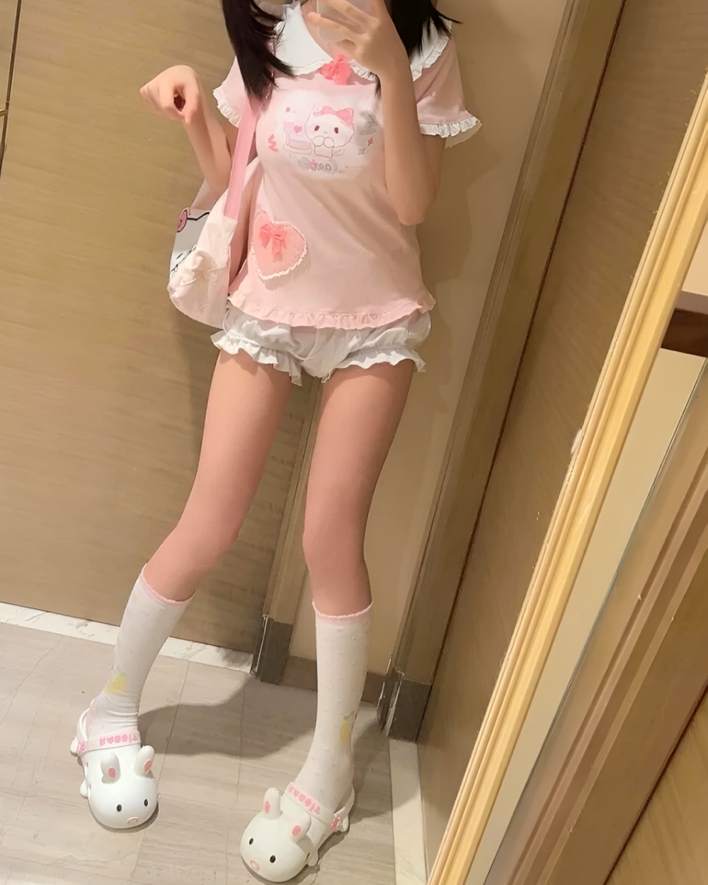 Person wearing a pink Kawaii Neko Tee, shorts, socks, and sandals. Cute design featuring a cat.