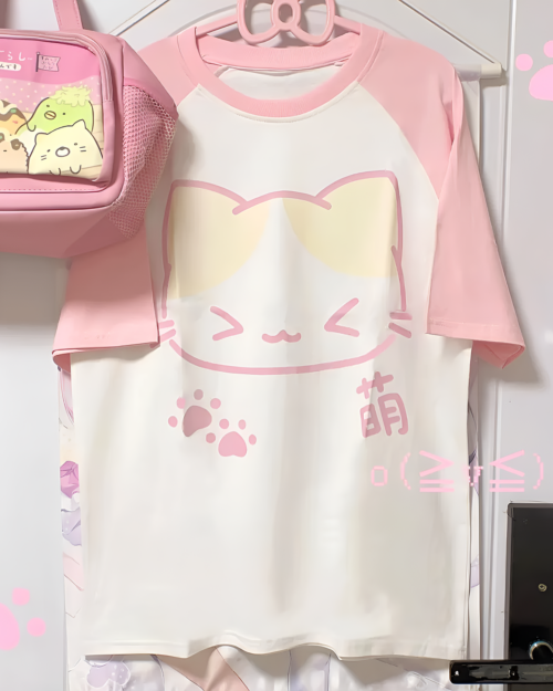 Kawaii Neko T-Shirt featuring a cat design on a light pink shirt. Includes paw prints and a cute face.