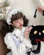 Woman holding a Kawaii Phantom Neko Bag, a black cat-shaped plush with a red bow. She's wearing a white bonnet and dress.