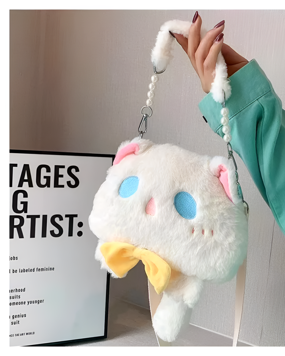Close-up of a Kawaii Phantom Neko Bag, a black shoulder bag with a cat face design and pearl strap. It is shown next to a poster.