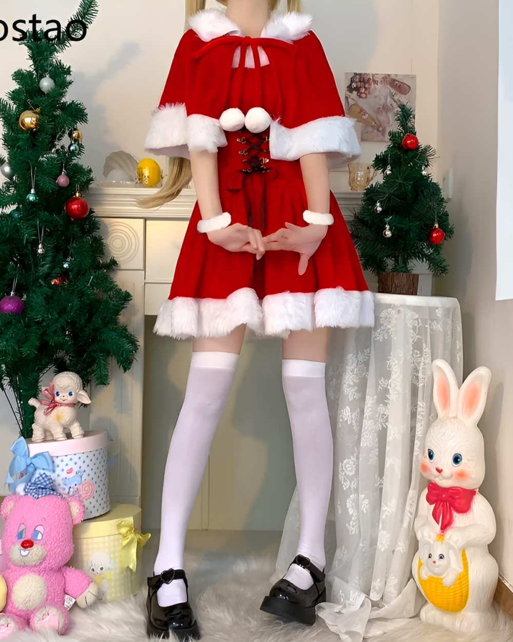 A woman wearing a red Kawaii Shawl Winter Dress with white fur trim, posing next to a Christmas tree and stuffed animals.