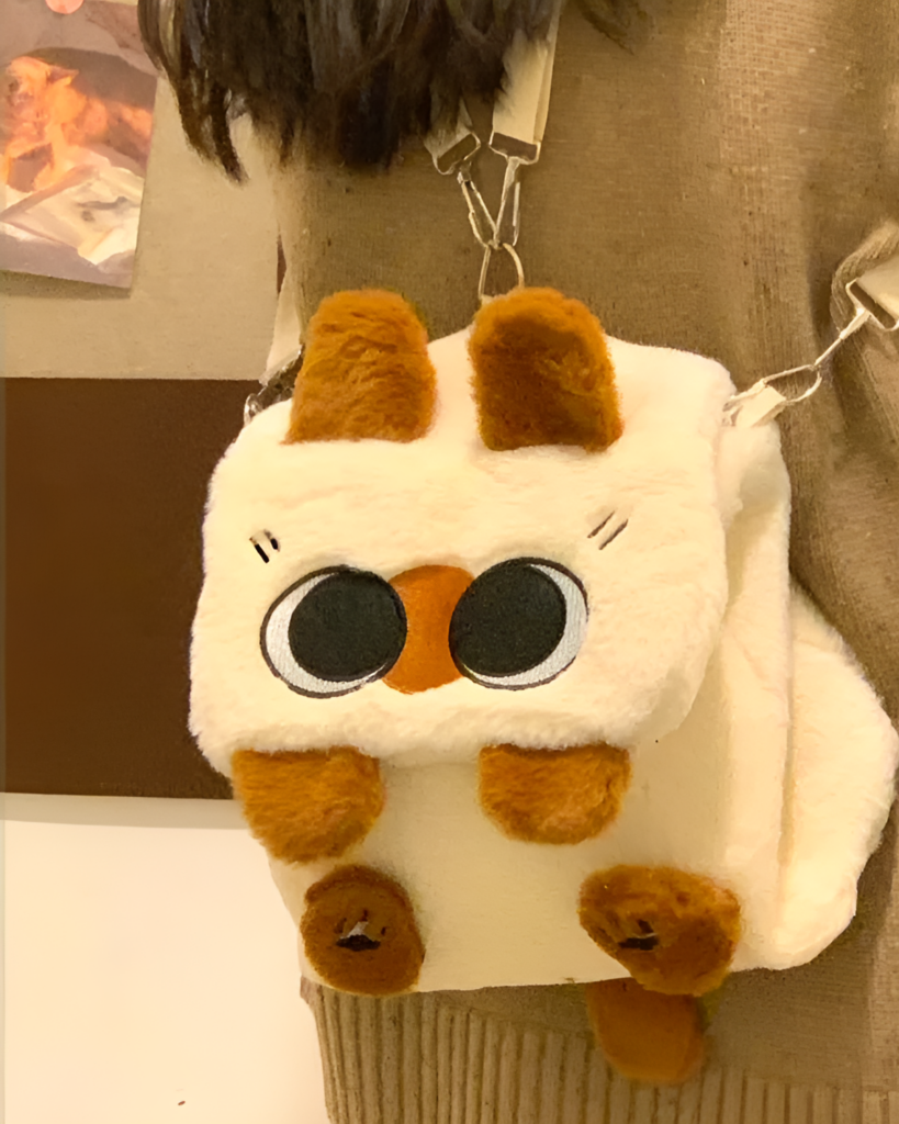 Close-up of a Kawaii Siamese Cat Plush Backpack with big eyes and brown ears.