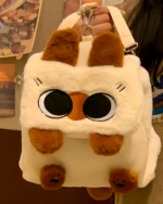 Close-up of a white and brown Kawaii Siamese Cat Plush Backpack with large eyes and paw details.
