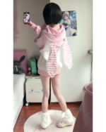 Woman wearing a pink strawberry bunny hoodie and matching bottoms, casual style.