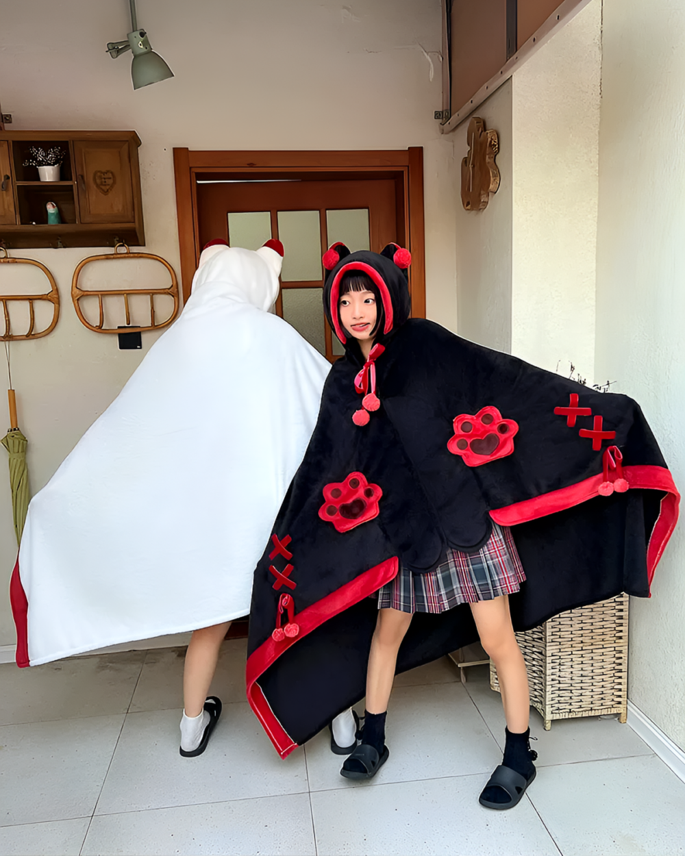 Girl wearing a black and white Kawaii Winged Eared Plush Cape with animal ears and paw prints.