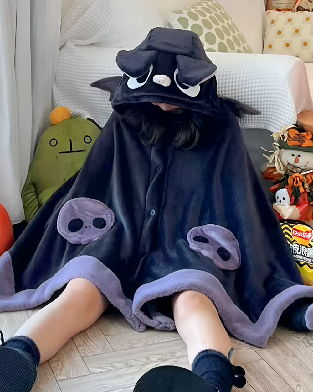 Child wearing a dark blue Kawaii Winged Eared Plush Cape with tentacle details and a hooded design. Plush toys are visible in the background.