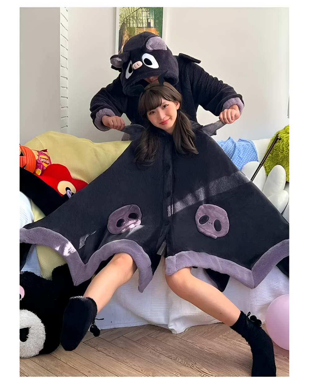 Woman wearing a black Kawaii Winged Eared Plush Cape with a hood and wing & ear details. Soft, fluffy texture.