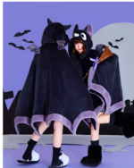 A person wearing a black Kawaii Winged Eared Plush Cape with purple trim and bat ears, against a purple backdrop.