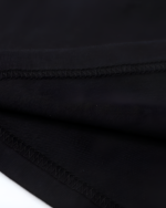 Close-up of the black fabric texture of the Chaos Neko Explosion Tee, showing the stitching details.