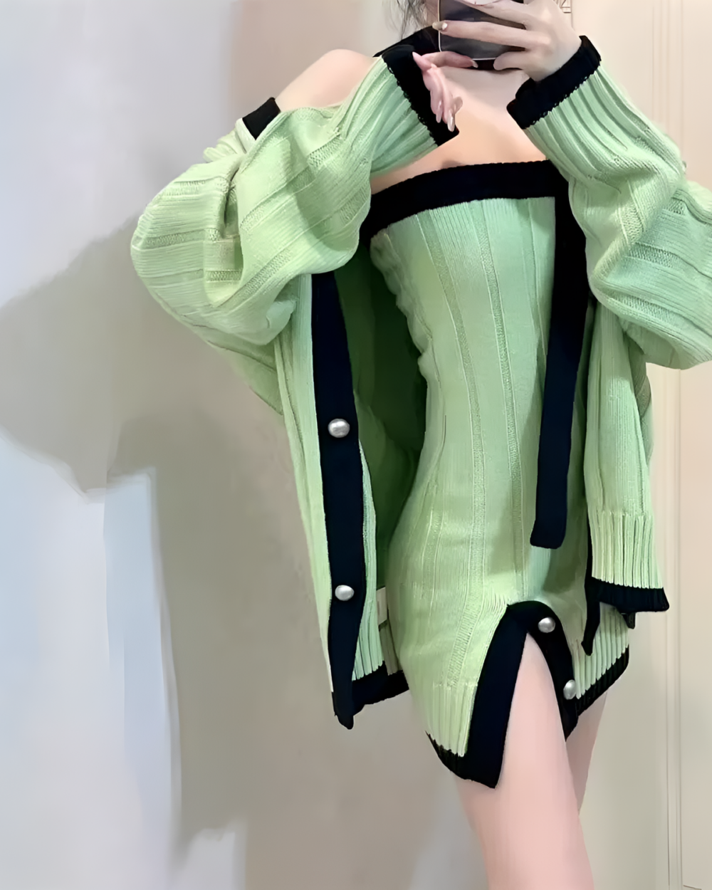 Chunky knit dress in pale green with black detailing, featuring puffed sleeves and button accents.