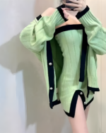 Chunky knit dress in pale green with black detailing, featuring puffed sleeves and button accents.