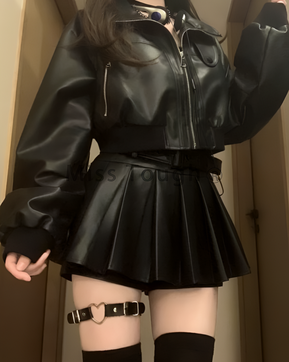 Black vegan leather two piece set featuring a jacket and skirt, worn by a model.