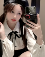Woman wearing a Korean preppy mini dress and beret, holding a phone.