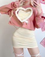 Woman wearing a pink Korean style mini dress coord with heart details. Includes a cropped hoodie and skirt set.