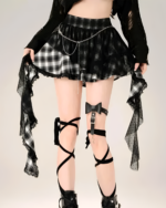 Model wearing a plaid goth punk skirt with lace trim & chain detail. Mini length, black & white checkered pattern.