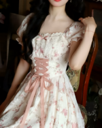 Close-up of a pink cottagecore dress with floral print, lace details, and a corset-style tie.