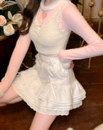 White sweater top with pink mini skirt, featuring ruffles and lace detailing.