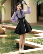 Model wearing a lavender Qi Lolita outfit, featuring a purple blouse and black pleated skirt with ribbon details.
