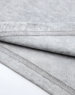 Close-up of a gray Kuro Neko T-Shirt showing detailed stitching on the hem. Soft fabric texture visible.